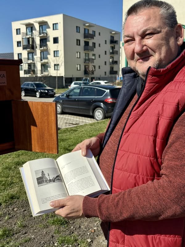 Milan Roman s knihou pri knižnej búdke na autobusovej stanici v Skalici