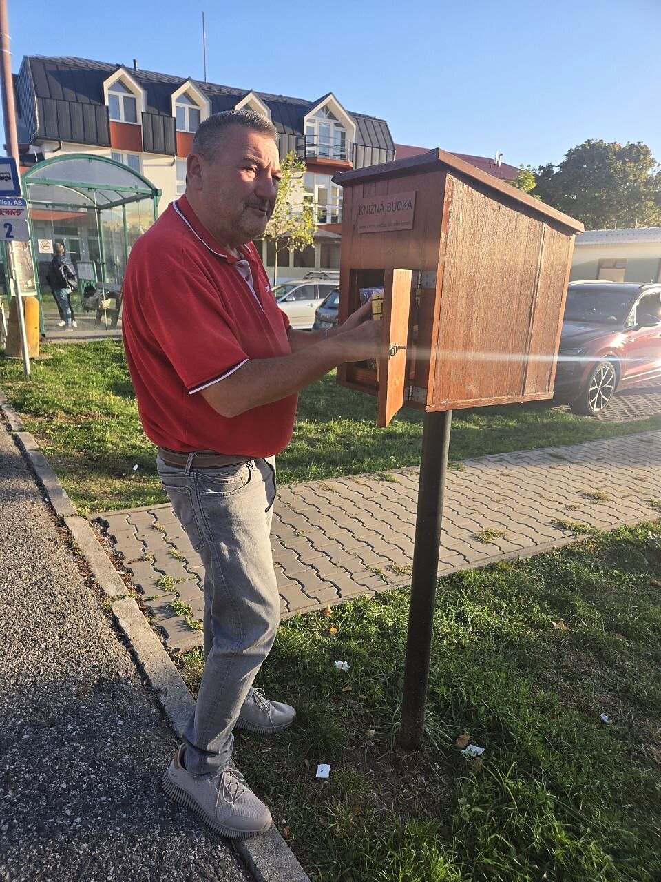 Milan Roman vkladá knihy do knižnej búdky pri zastávke na autobusovej stanici v Skalici